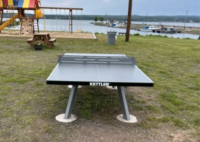 Ping pong table at Capul Park with playground equipment, picnic table, and marina in background in Baraga County Michigan